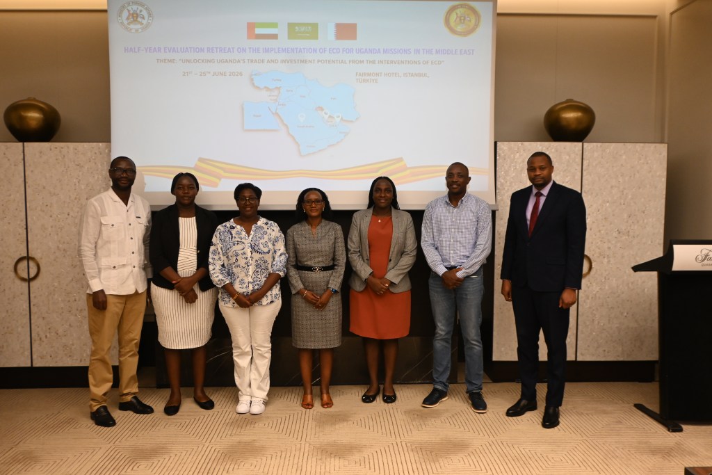 Group of six individuals standing in front of a presentation backdrop at a conference titled 'Half-Year Evaluation Retreat on the Implementation of ECD for Uganda Missions in the Middle East'.